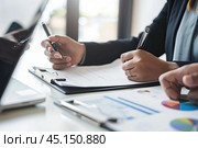 The business team holds a joint meeting, drawing up financial schedules at a desk. The concept of increasing the efficiency of the company and team cohesion. Стоковое AI-изображение, AI-художник Ярославский Максим / Фотобанк Лори