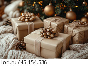 Beautifully wrapped Christmas presents decorated with shiny gold ribbons and bows. The presents lie on a soft knitted blanket, creating a cozy and warm atmosphere. In the background, a festively decorated Christmas tree with twinkling lights and golden baubles is visible. Warm gold and beige tones give the scene elegance and a festive mood. This image perfectly conveys the atmosphere of Christmas and is ideal for use in holiday projects, advertising, design and websites dedicated to the winter holidays. Стоковое AI-изображение, AI-художник Анна Кривицкая / Фотобанк Лори