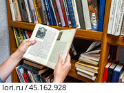 Женщина выбирает книгу для чтения из коллекции библиотеки. Редакционное фото, фотограф Александр Бушков / Фотобанк Лори