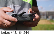 a surveyor on a construction site controls a quadcopter. Стоковое видео, видеограф Igor Skripachev / Фотобанк Лори