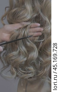 Vertical video of woman stylist combing long wavy blond female hair from back side. Стоковое видео, видеограф Сергей Пристяжнюк (Serg Zastavkin) / Фотобанк Лори