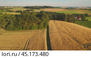 A scenic aerial view of a countryside with patches of forest, golden fields, and scattered houses, bathed in warm evening light, capturing a peaceful rural setting. Стоковое видео, видеограф Igor Tichonow / Фотобанк Лори