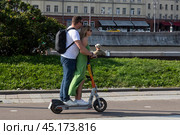 Люди катаются на электросамокате компании Whoosh по Крымской набережной в центре города Москвы в летний, солнечный день, Россия (2024 год). Редакционное фото, фотограф Николай Винокуров / Фотобанк Лори