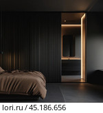 A modern minimalist bedroom interior with a predominance of dark tones. The bed is covered with plain brown bed linen, and a black ribbed panel is installed on the wall next to it, which adds a textural element to the design of the room. On the right, you can see the door leading to the bathroom with soft built-in lighting, which creates an atmosphere of coziness and modernity. The overall design of the room conveys a stylish, laconic and sophisticated design with an emphasis on simplicity and functionality. Стоковое AI-изображение, AI-художник Анна Кривицкая / Фотобанк Лори