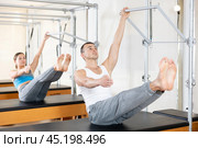 Man doing abdominal exercises on trapeze table at pilates class. Стоковое фото, фотограф Яков Филимонов / Фотобанк Лори