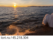 Beautiful landscape of Baikal Lake in December at sunset. Waves crash of icy pier against backdrop of setting sun. Natural background. Outdoor recreation and lake travel. Стоковое фото, фотограф Виктория Катьянова / Фотобанк Лори