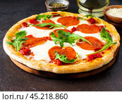 hot homemade Italian pizza margherita with mozzarella and tomatoes on dark brown stone table, side view. Стоковое фото, фотограф Natalia Gdovskaia / Фотобанк Лори