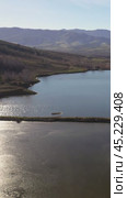 Vertical drone video of flying over a hilly rural landscape with a winding road and fish ponds. Altai Krai. Стоковое видео, видеограф Сергей Пристяжнюк (Serg Zastavkin) / Фотобанк Лори