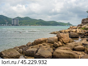 Nha Trang Vietnamese resort coastline is revealed in vibrant spectacle. picturesque rocky coast meet azure sea under radiant sun, panorama of beaches and crystal-clear waters. Стоковое фото, фотограф Павел Муравьев / Фотобанк Лори