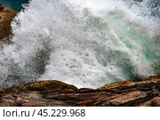 Powerful waves crash against rugged boulders and stones, creating dynamic spectacle of nature raw force. tumultuous sea surges, sending salty spray into air, as waves collide with coastal formations. Стоковое фото, фотограф Павел Муравьев / Фотобанк Лори