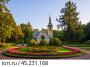 Кирха Преображения Господня, город Зеленогорск, Курортный район Санкт-Петербурга, Россия. Вид на красивую протестантскую церковь с колокольней. На переднем плане цветочные клумбы в сквере Победы. Лютеранская церковь Преображения Господня построена в 1908 году по проекту архитектора Йозефа Стенбека. Архитектурная достопримечательность Зеленогорска. Стоковое фото, фотограф Андрей Степанов / Фотобанк Лори