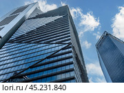 Singapore, 24 January 2024: Skyscrapers rise majestically, symbolizing global business prowess. Viewed from below against backdrop of blue sky and clouds. Редакционное фото, фотограф Павел Муравьев / Фотобанк Лори