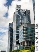 Singapore, 24 January 2024: Skyscrapers rise majestically, symbolizing global business prowess. Viewed from below against backdrop of blue sky and clouds. vertical photo. Редакционное фото, фотограф Павел Муравьев / Фотобанк Лори