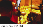 A drummer behind a drum kit with cymbals standing out in the foreground. In the background, warm yellow light from a multitude of candles. A candlelit concert. Стоковое видео, видеограф Воловодов Владимир / Фотобанк Лори
