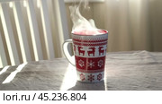 Steaming Cup of Coffee or Tea on Table. White linen Tablecloth. Close up ceramic red Christmas mug with smoke on old table in dining room interior background. Hot Drink Concept. Cozy Morning. Стоковое видео, видеограф Марина Демидюк / Фотобанк Лори