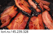 Frying Bacon Slices in a Pan. Crispy Pieces of Delicious Red Thin Smokey Bacon Fried in a Hot Skillet. Traditional Breakfast. Smoked Bacon Rasher or Strip Being Cooked. Grill. Fat High Calorie Food. Стоковое видео, видеограф Марина Демидюк / Фотобанк Лори