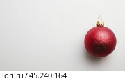 A red Christmas ball on a white background. New Year's Eve. This is a close-up of a free-standing red ball, free space for text. Стоковое AI-изображение, AI-художник Елена Зубкова / Фотобанк Лори
