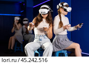 Girls wearing virtual reality glasses play in pairs, against each other, manipulating objects or shooting at targets using joysticks in their hands. Стоковое фото, фотограф Яков Филимонов / Фотобанк Лори