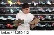 Young man choose summer shoes for hiking, reliable and stable shoes for long walks on tourist trails and routes. Стоковое видео, видеограф Яков Филимонов / Фотобанк Лори