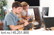 Engrossed in his work, student sits near computer, fully immersed in his studies. Стоковое видео, видеограф Яков Филимонов / Фотобанк Лори