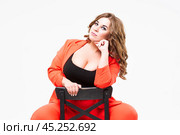 Plus size model with big breast and deep decollete, fat woman on white background in orange pantsuit, body positive concept. Стоковое фото, фотограф Станислав Тарко / Фотобанк Лори