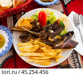 Delicious browned grilled lamb ribs served with crispy french fries and lettuce with tomato on plate, decorated with lemon. Стоковое фото, фотограф Яков Филимонов / Фотобанк Лори