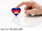 Cambodia flag. Love and respect Cambodia. A man's hand holds a heart in the shape of the Cambodia flag on a white glass surface. The concept of patriotism and tourism. Стоковое фото, фотограф Никита Бурденков / Фотобанк Лори