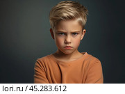 Portrait of disgruntled blond boy against grey background. The boy experiencing negative emotions due to fact that his family tore him away from computer games and forced him. Sulking Caucasian boy. Стоковое AI-изображение, AI-художник Sergey Grishin / Фотобанк Лори