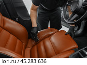Cleaning a leather car seat with a brush and detergent. A man in black rubber gloves cleans the chair. Detailing studio. Стоковое фото, фотограф Владислав Тригуб / Фотобанк Лори