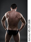 Handsome muscular bodybuilder posing on gray background. Low key studio shot. Стоковое фото, фотограф Станислав Тарко / Фотобанк Лори