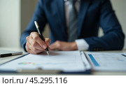 Close-up view business executive blue suit reviewing signing important document, focus on hand pen ready to write, concept of agreement finalization, legal paperwork completion in corporate setting. Стоковое AI-изображение, AI-художник Павел Муравьев / Фотобанк Лори