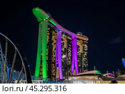 Marina Bay Sands hotel in Singapore of light at night, its bright illumination reflected in waters. ArtScience Museum and Helix Bridge join luminous cityscape. Редакционное фото, фотограф Павел Муравьев / Фотобанк Лори