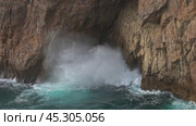 Sea waves enter a cave in rock and form splashes. Стоковое видео, видеограф Михаил Коханчиков / Фотобанк Лори