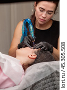 Cosmetologist applying permanent eyebrow makeup on a client. Стоковое фото, фотограф Юрий Поздников / Фотобанк Лори