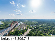 Aerial view of the colorful bridge over a river with urban development and greenery under a bright sky in a bustling city. Стоковое фото, фотограф Алексей Климкин / Фотобанк Лори