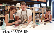 During master class, student paints clay vessel under guidance of male teacher. Стоковое видео, видеограф Яков Филимонов / Фотобанк Лори