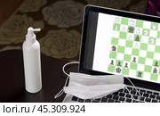 Chess task on laptop screen online. Near antibacterial spray and medical mask. Leisure in self-isolation. International chess day. Стоковое фото, фотограф Vadzim Yakubovich / Фотобанк Лори