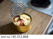 Rustic scene features an open tin can of beef stew, its surface glistening with a layer of fat. The image evokes thoughts of comfort, sustenance, and traditional hearty meals. Стоковое фото, фотограф Татьяна Степанищева / Фотобанк Лори