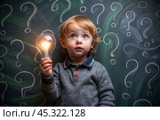 Development and education of children. A thoughtful boy on a dark background with a light bulb and question marks . Brainstorming and the concept of an idea. Стоковое AI-изображение, AI-художник Photojuli / Фотобанк Лори