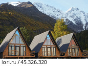 Autumn mountain tourism. Triangular chalets for tourists on the background of picturesque mountains with snow-covered rocky peaks. Стоковое фото, фотограф Роман Дзюбало / Фотобанк Лори
