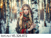 A beautiful girl in a traditional Russian folk shawl in a winter birch grove. The portrait symbolizes the traditions and beauty of the Russian people. Стоковое AI-изображение, AI-художник Photojuli / Фотобанк Лори
