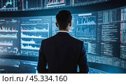 Business professional analyzing financial data on multiple computer screens in dark control room, market trends monitoring, corporate strategy planning. Стоковое фото, фотограф Павел Муравьев / Фотобанк Лори