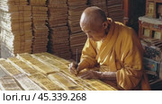 Buddhist monk carefully hand-writing ancient texts in monastery library. Стоковое AI-видео, аниматор Юрий Поздников / Фотобанк Лори