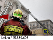Сотрудник пожарного расчета принимает участие в тушении пожара в центре города Москвы, Россия. Редакционное фото, фотограф Николай Винокуров / Фотобанк Лори