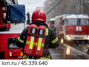 Сотрудник пожарного расчета принимает участие в тушении пожара в центре города Москвы, Россия. Редакционное фото, фотограф Николай Винокуров / Фотобанк Лори