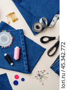 Sewing supplies and denim fabric arranged on a workspace for clothing alterations in a bright setting. Стоковое фото, фотограф Сергей Толмачёв / Фотобанк Лори