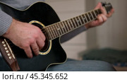 Playing the guitar. Strumming acoustic guitar. Musician plays music. Man fingers holding mediator. Man hand playing guitar neck in dark room. Unrecognizable person rehearsing, fretboard close-up. Стоковое видео, видеограф Марина Демидюк / Фотобанк Лори