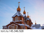 Wooden orthodox cathedral close-up. Bottom up view of the gilded domes with crosses. Christianity in Siberia and the Far North of Russia. Cathedral of the Holy Trinity, Anadyr, Chukotka, Russia. Стоковое фото, фотограф Андрей Степанов / Фотобанк Лори
