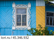 Beautiful traditional Russian ornaments on the window frames. Window and blue wall of a wooden house in the countryside. Traditional decoration of country houses in Russia. Vologda region, Russia. Стоковое фото, фотограф Андрей Степанов / Фотобанк Лори