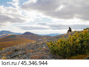 Chukotka, Far North of Russia. An elderly man sits on a hillside and looks thoughtfully aside at the mountains. A lonely person surrounded by nature. Autumn arctic landscape. Редакционное фото, фотограф Андрей Степанов / Фотобанк Лори